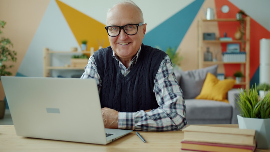 Smiling elderly man with glasses at laptop computer